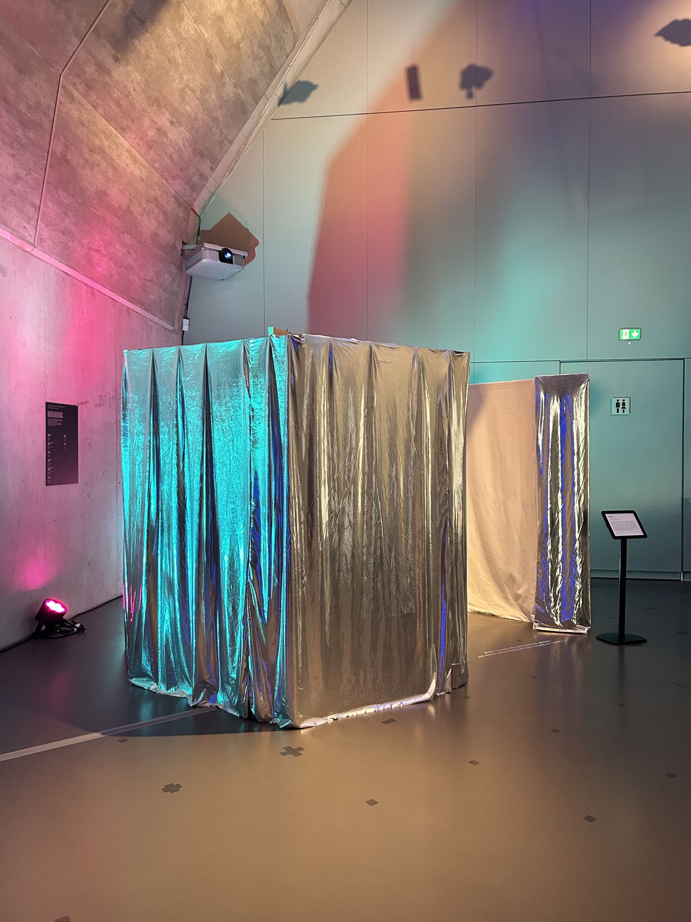 Die silberne Kabine im Museumsraum, türkis und pink angestrahlt.